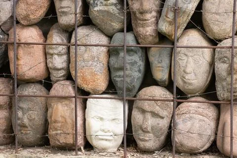 A wall of stones in the shape of human faces Stock Photos