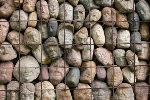A wall of stones in the shape of human faces Stock Photos