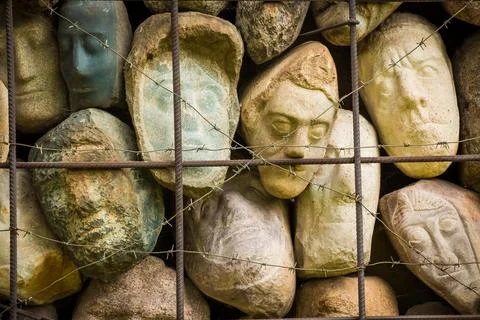 A wall of stones in the shape of human faces Stock Photos