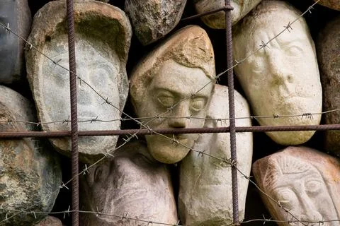 A wall of stones in the shape of human faces Stock Photos