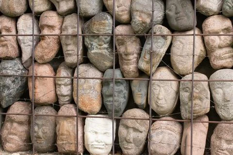 A wall of stones in the shape of human faces Stock Photos