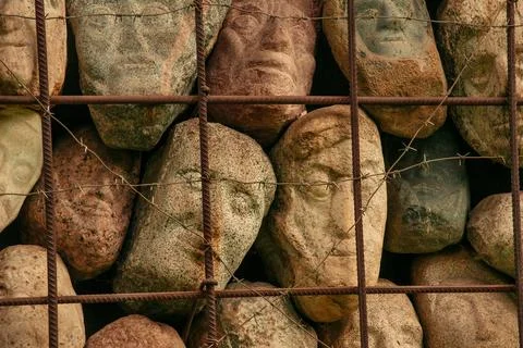 A wall of stones in the shape of human faces Stock Photos