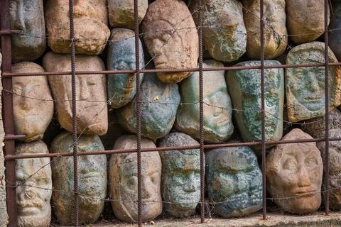 A wall of stones in the shape of human faces Stock Photos