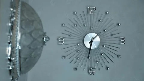 On the wall there is a modern beautiful mechanical clock and chrome glass lamp Stock Footage 297750379