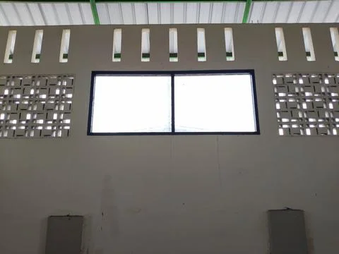 A wall with two large windows and several ventilation holes Stock Photos