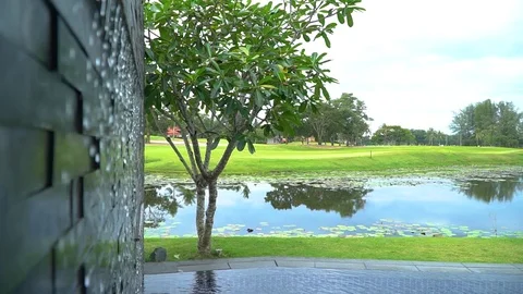 A wall waterfall in the pool with a view of the pond and a green golf course. Stock Footage 85569293