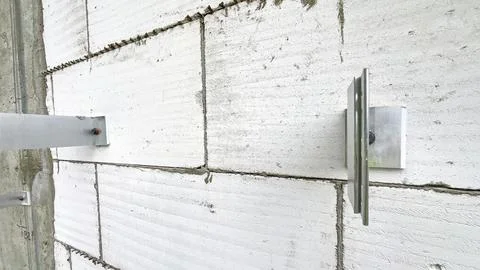 A wall with a white brick pattern and a metal bracket Stock Photos