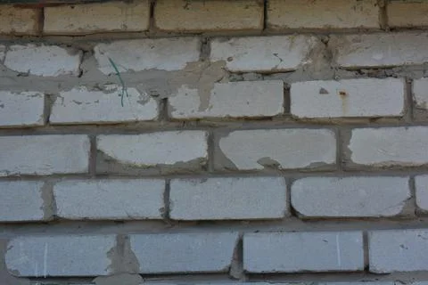 Wall of white smooth brick with gray cement masonry, construction error. Stock Photos