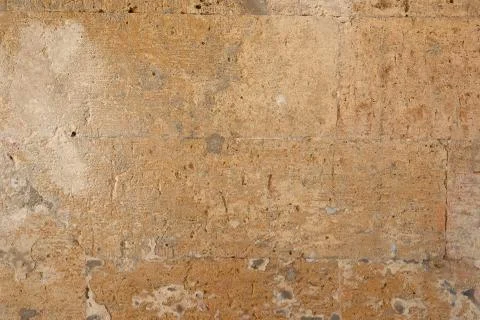 Wall of yellow rectangular stones with cement, fragment of ancient architectu Stock Photos