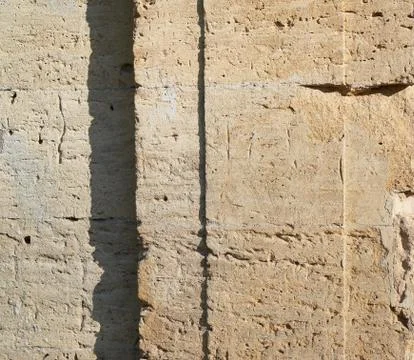 Wall of yellow rectangular stones with cement, fragment of ancient architectu Stock Photos