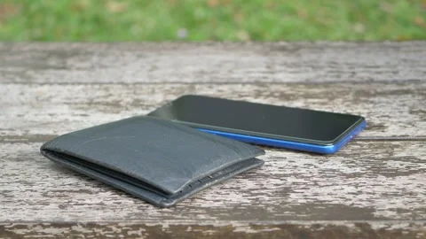 Wallet and smartphone resting on weathered wooden table outdoors close up s.. Stock Footage 332578726