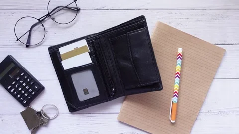 Wallet with credit cards, notebook and pen on a wooden table, top down view. Stock Footage 332473134
