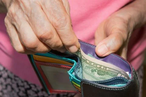 Wallet with dollars close-up. a middle-aged lady keeps pulling money out of h Stock Photos