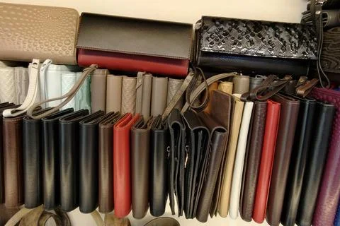 Wallets and purses of various colors and styles are arranged neatly on a shel Stock Photos