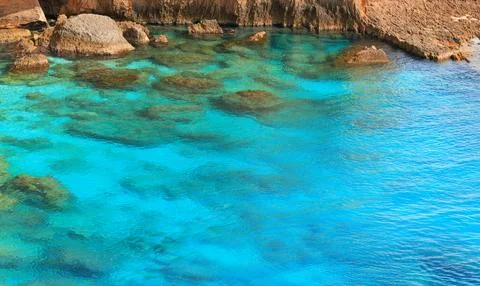Wallpaper pattern transparent water texture with rocky stone shore line cliff Stock Photos