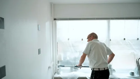 Walls gets painted with a paint roller by senior man working hard Stock Footage 107265658