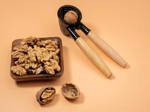 Walnut and nutcracker on orange background. Raw walnut. Stock Photos