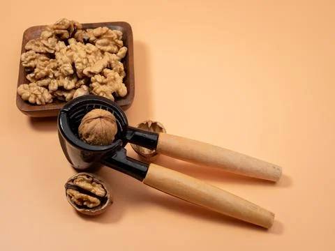 Walnut and nutcracker on orange background. Raw walnut. Stock Photos