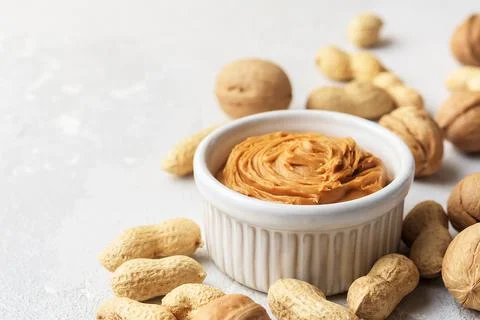 Walnut butter made of peanuts, almonds and walnut on a grey background. Stock Photos