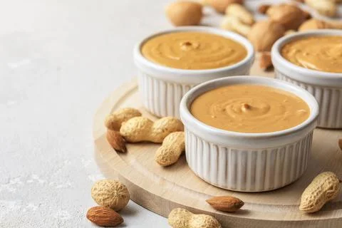 Walnut butter made of peanuts, almonds and walnut on a grey background. Stock Photos