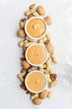 Walnut butter made of peanuts, almonds and walnut on a grey background. Stock Photos