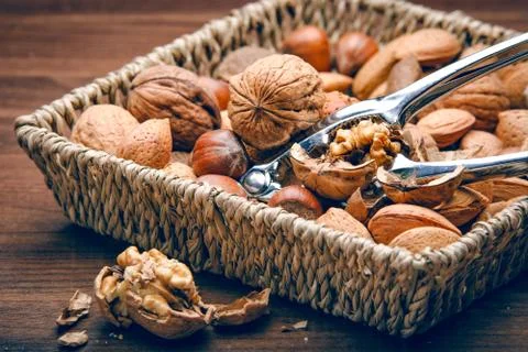 Walnut cracker sitting in basket full of nuts Stock Photos