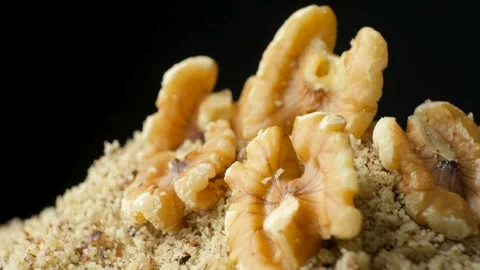 Walnut halves on ground walnut kernels flour rotate on black background Stock Footage 327149501