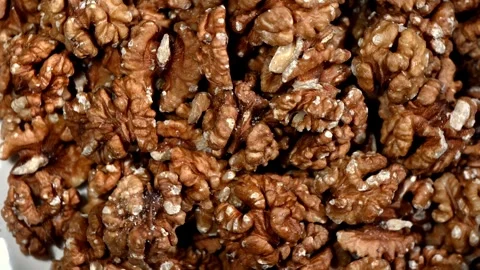 Walnut halves rotating on marble, brain-like texture, overhead view Stock Footage 326816493