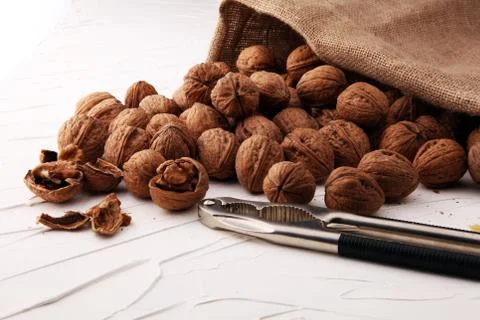 Walnut kernels and whole walnuts on table with a nutcracker Stock Photos
