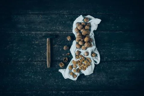 Walnut kernels and whole walnuts with a hammer on a rustic old wood table . Stock Photos