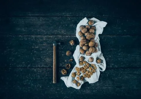 Walnut kernels and whole walnuts with a hammer on a rustic old wood table . Stock Photos