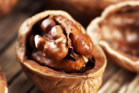 Walnut kernels and whole walnuts on rustic old table Stock Photos