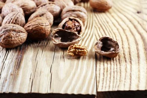 Walnut kernels and whole walnuts on rustic old table Stock Photos