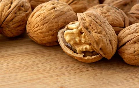 Walnut kernels and whole walnuts on wooden table Stock Photos
