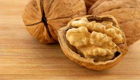 Walnut kernels and whole walnuts on wooden table Stock Photos