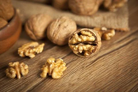 Walnut kernels and whole walnuts on rustic old wooden table Stock Photos
