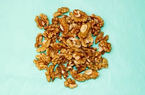 Walnut kernels are piled up close-up on a turquoise background. Stock Photos