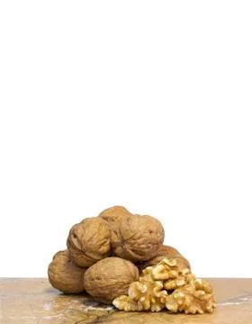 Walnut kernels in front of pile of walnut shells on top of marble surface. White Stock Photos