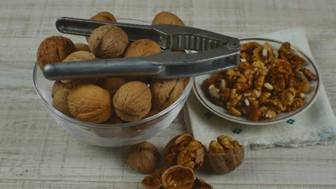 Walnut kernels on white glass saucer, unpeeled walnuts in transparent glass bowl Stock Footage 222685733