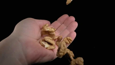 The walnut kernels will fall into the hand on a black background. Super slow Видео 149242493