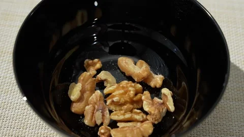 Walnut Pieces Rotating in a Black Bowl. Natural Snack Showcase Stock Footage 340960582