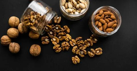 Walnut scattered on the black table from a jar. Walnut is a healthy vegetarian Stock Photos