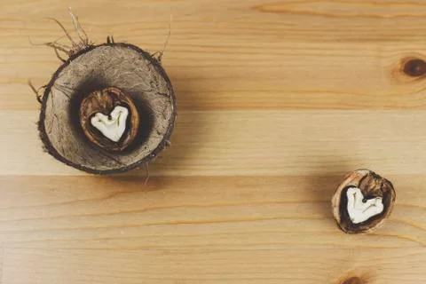 Walnut in the shape of a heart lies in the shell of a coconut Stockfoto's