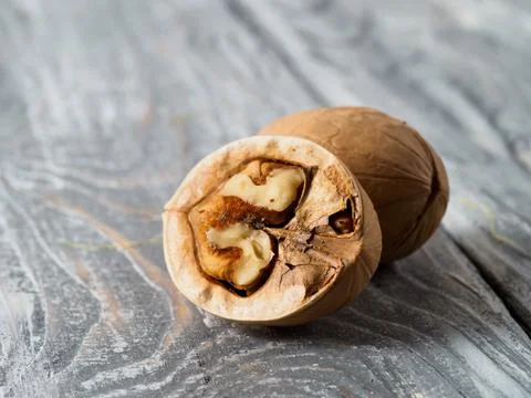 Walnut with shell on wooden background. Stock Photos