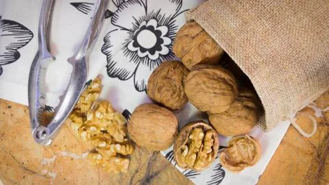 Walnut shells and kernels in burlap sack on marble surface with white towel with Stock Photos