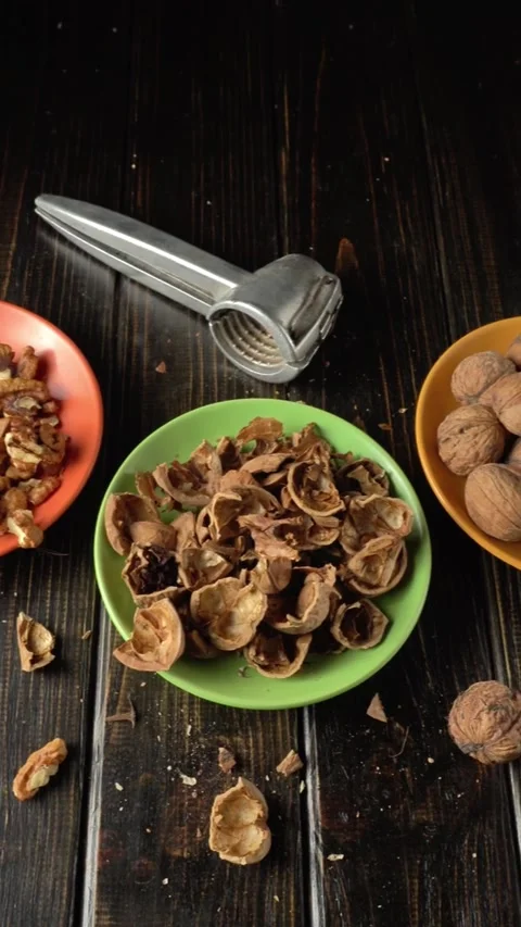 Walnut shells and nutcracker on wooden table with scattered shells and nuts in Video stock 328237612