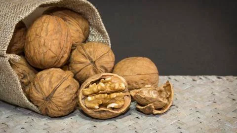 Walnut shells and walnut kernels in burlap sack on light wicker surface. Great 写真素材