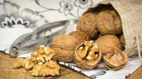Walnut shells and walnut kernels bursting out of burlap sack on top of marble Stock Photos