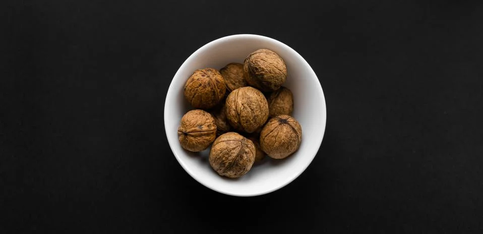 Walnut in a small plate on a black table. Walnuts is a healthy vegetarian Stock Photos