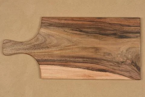 Walnut wooden serving board with handle on brown background Stock Photos